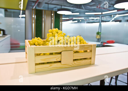 Grappes de raisins dans une boîte en bois sur une table dans la cuisine Banque D'Images