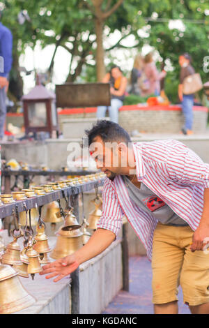 Pokhara, Népal, 10 octobre 2017 non identifié : businessman touching les cloches de tailles différentes en barahi taal mandir, Pokhara, Népal Banque D'Images