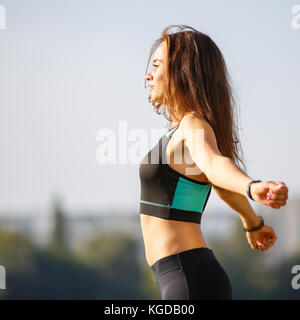 Portrait of young woman l'échauffement avant le jogging dans le parc près du lac. portrait de athletic girl in black top après l'entraînement de fitness Banque D'Images