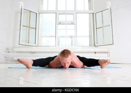 Bel homme sportif pratiquant le yoga. asana kurmasana. tortue tortue posture pose. Banque D'Images