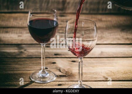 Verser le vin rouge dans un verre sur une table en bois Banque D'Images