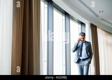 Mature businessman with smartphone dans un hôtel. Banque D'Images