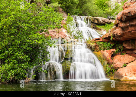 Cascades cascade sur les rochers rouges en vertu de l'Espai Natural Sant Miquel del Fai monastère en Catalogne, Espagne. Banque D'Images