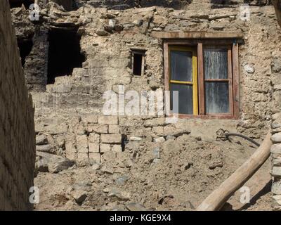 L'ancienne maison de brique moitié en ruine, le mur de l'ouvertures noir pierres effondrée, la fenêtre avec l'ancien cadre en bois, le brun et de couleur jaune vif. Banque D'Images