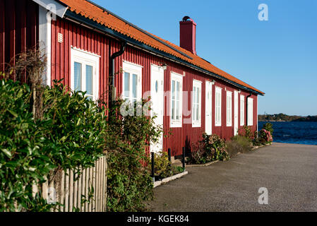 Karlskrona, Suède - 30 octobre 2017 : documentaire sur la vie quotidienne et l'environnement. Appartements en bord de mer dans une maison en bois rouge. Côte en arrière-plan. Banque D'Images