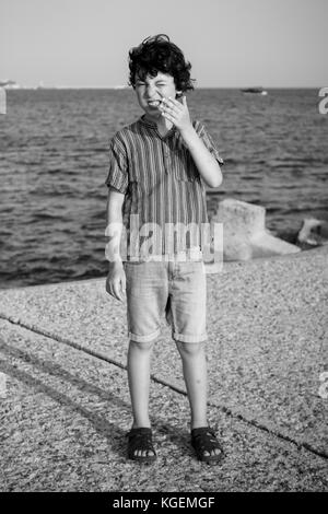 Un garçon est debout près de la mer. noir et blanc. Banque D'Images