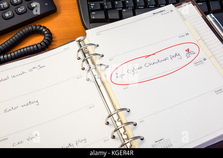 Un agenda de bureau avec une entrée pour la fête de Noël de bureau entouré en rouge. Banque D'Images