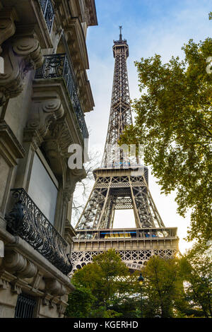 Vue de la majestueuse Tour Eiffel dans son voisinage immédiat avec les arbres et bâtiments typiquement parisienne au premier plan. Banque D'Images