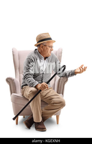 Homme mature avec une canne assise sur un fauteuil et parler isolé sur fond blanc Banque D'Images