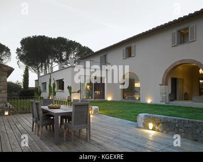 Vue sur une maison de campagne classique rénovée en Toscane. Jardin avec table et chaises au coucher du soleil Banque D'Images