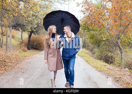 Un gars avec une fille rendez-vous sous la pluie parapluie Banque D'Images