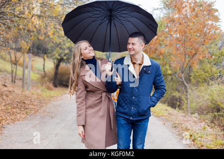 Un gars avec une fille rendez-vous sous la pluie parapluie Banque D'Images