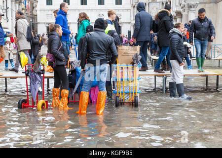 Venise, Vénétie, Italie. Nov 7, 2017. Acqua Alta marée haute de 115cm à partir de la lagune provoquant des inondations temporaires sur la Piazza San Marco. Passerelle, ou des passerelles, sont installés à la circulation des piétons. Les vendeurs de rue vendent des couvre-chaussures jetables en plastique pour les touristes. Credit : Mary Clarke/Alamy Live News Banque D'Images