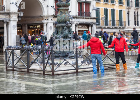 Venise, Vénétie, Italie. Nov 7, 2017. Acqua Alta marée haute de 115cm à partir de la lagune provoquant des inondations temporaires sur la Piazza San Marco. Passerelle, ou des passerelles, sont installés à la circulation des piétons. Les touristes attirés par les pigeons se rassemblaient qui essaient de garder au sec au pied d'un mât. Credit : Mary Clarke/Alamy Live News Banque D'Images