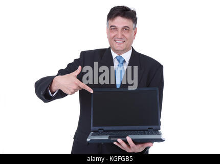 Senior businessman holding laptop et en pointant l'écran vide, isolé sur fond blanc Banque D'Images