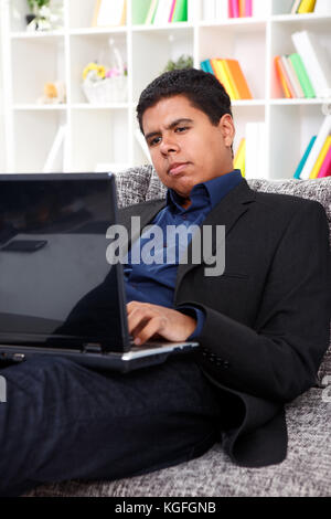 Young businessman using laptop at home à la recherche à l'écran Banque D'Images