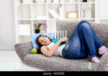 Fatigué teenage girl sleeping on sofa at home Banque D'Images