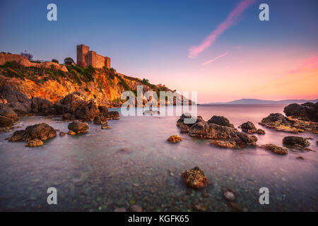 Talamone rock beach et forteresse médiévale rocca aldobrandesca murs et au coucher du soleil. maremma argentario destination touristique italien. toscane, italie. Banque D'Images