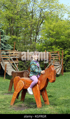 Happy little girl riding cheval de bois Banque D'Images