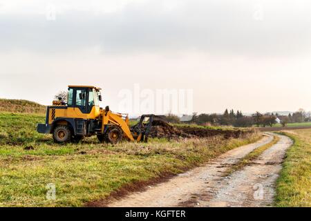 Drague avec un peu de fumier remorque chargement pour le champ de la fécondation. machine agricole pour la fertilisation de la bouse de vache. Banque D'Images