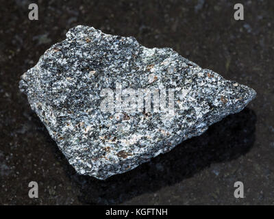 La prise de vue macro des eaux minérales naturelles rock specimen - syénite à néphéline rugueux sur la pierre de granit sombre contexte Banque D'Images