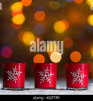 Ensemble de 3 bougies debout dans la neige avec defocused fairy lights, orange ou flou d'or dans l'arrière-plan, arrière-plan de noël avec copyspace Banque D'Images