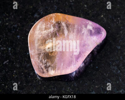 La prise de vue macro des eaux minérales naturelles rock specimen - poli l'ametrine gemstone sur arrière-plan en granit sombre du brésil Banque D'Images