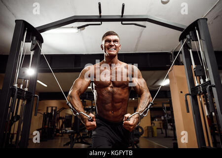 Bodybuilder travaille sur sa poitrine avec cable crossover dans une salle de sport. Banque D'Images