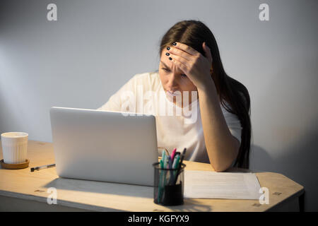 Des jeunes adultes en difficulté de lecture au sujet de problème récent femme ordinateur portable en fin de soirée, trouver meilleur plan d'actions au fond de pensées. dernière minut Banque D'Images