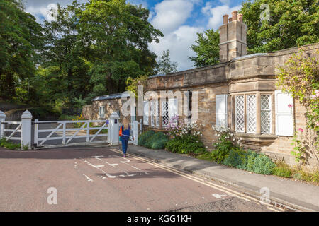 Une femme fait son chemin passé l'ancien Cottage sans frais et Gate sur Quarryheads lane, à l'égard de Bailey et Prebends bridge, Durham, Royaume-Uni Banque D'Images