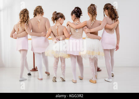 Un groupe de petites filles en robes pendant le cours. vue arrière. Banque D'Images