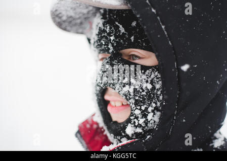 Enfant portant un masque de ski couverte de neige Banque D'Images