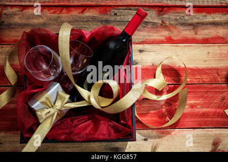 Valentines Day concept. Bouteille de vin rouge, des lunettes et un cadeau dans une boîte en bois, avec fond copyspace Banque D'Images