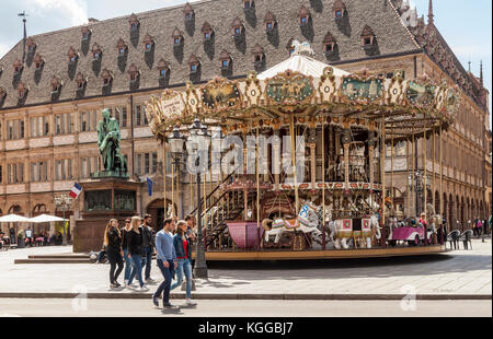 Place Gutenberg, Strasbourg. Personnes passant le carrousel à deux étages, statue de l'imprimeur, Johannes Gutenberg. Alsace, France. Banque D'Images