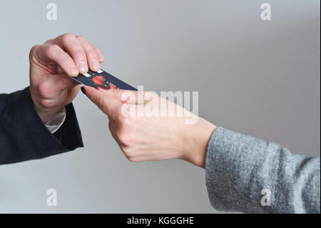 A woman's hand est de donner une carte de crédit et la main d'un homme est de le prendre. Banque D'Images