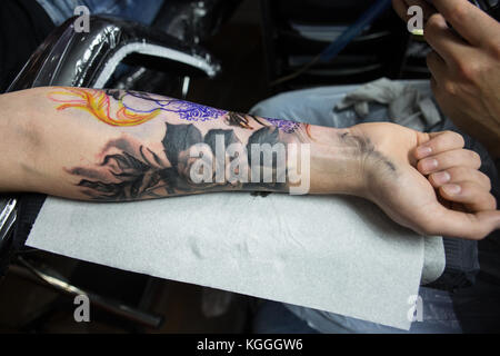 Un tatoueur au travail,un artiste de tatouage encres un conçu sur le dos d'une fille locale dans son studio à Londres. Banque D'Images