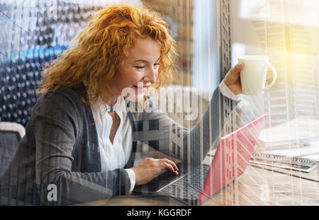 Cheerful woman having coffee en surfant sur le web Banque D'Images