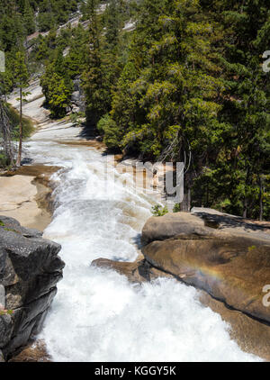 Un petit arc-en-ciel sur la rivière Merced à Yosemite National Park avec ses nombreuses cascades, il serpente à travers le parc. Banque D'Images