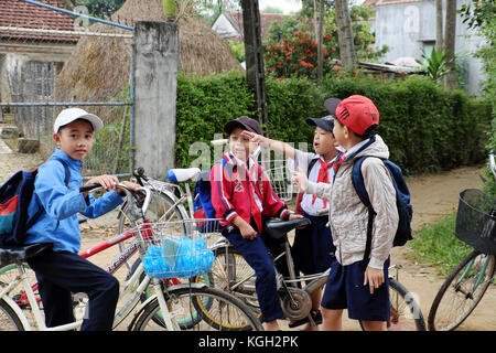 Binh Dinh, le Viet Nam, groupe d'enfants d'asie se tenir ensemble après l'école à bicyclette, à campagne vietnamienne, élève le vélo pour aller à l'école Banque D'Images