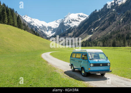 Oberstdorf, Bavière, Allemagne - 10 mai 2017 : bleu et blanc vintage vw bully camping car la conduite sur la route de la vallée de montagne dans la vallée de trettachtal, allgauer alpes. Banque D'Images