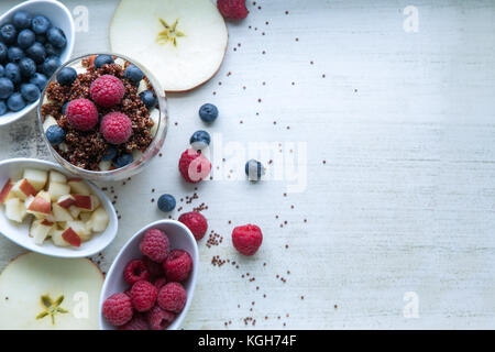 Le quinoa rouge cuit avec des baies et apple petit-déjeuner dans un verre, peu de bols de framboises, bleuets et pommes hachées, des tranches de pomme, voir Banque D'Images