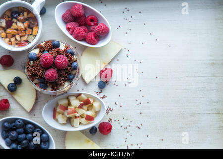 Le quinoa rouge cuit avec des baies et apple petit-déjeuner dans un verre, peu de bols de framboises, bleuets et pommes hachées, des tranches de pomme, voir Banque D'Images