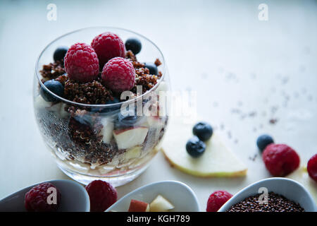 Le quinoa rouge cuit avec des baies et apple petit-déjeuner dans un verre, peu de bols de framboises, bleuets et pommes hachées, des tranches de pomme, voir Banque D'Images