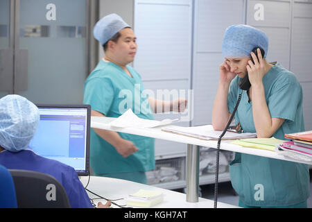 Nurse talking sur un téléphone dans un hôpital occupé au Royaume-Uni. Banque D'Images