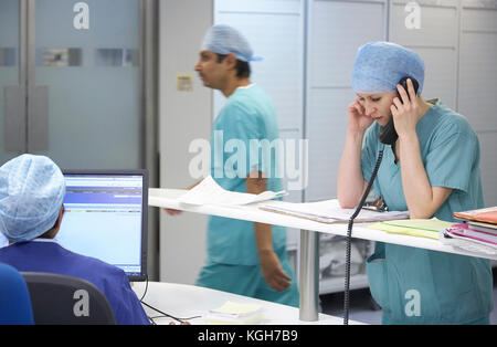 Nurse talking sur un téléphone dans un hôpital occupé au Royaume-Uni. Banque D'Images