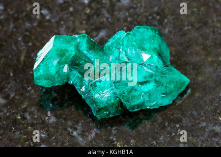 La prise de vue macro des eaux minérales naturelles et des matières premières - spécimen rock crystal dioptase sur pierre de granit sombre arrière-plan d'Altyn-tyube mine, région de Karaganda, Banque D'Images