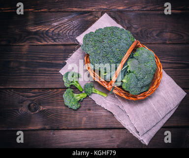 Le brocoli chou frais dans un panier en osier marron sur une table en bois, vue du dessus, l'espace vide sur la gauche, la tonalité vintage Banque D'Images