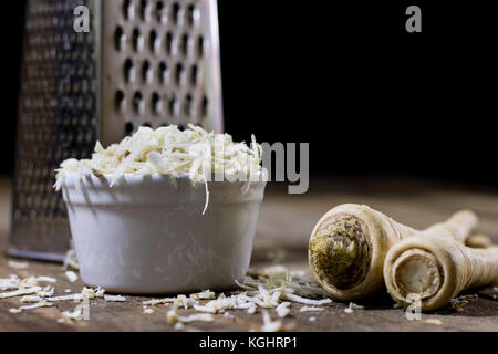 Racine de persil racine sur la grille et le persil. râpe sur la vieille table de cuisine dans la cuisine. fond noir Banque D'Images