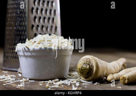 Racine de persil racine sur la grille et le persil. râpe sur la vieille table de cuisine dans la cuisine. fond noir Banque D'Images