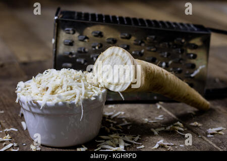 Racine de persil racine sur la grille et le persil. râpe sur la vieille table de cuisine dans la cuisine. fond noir Banque D'Images